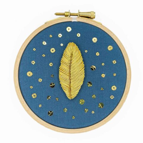 goldwork embroidery leaf with spangles on blue fabric in a wooden hoop