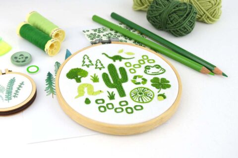 Several folk art objects embroidered in green in a wooden hoop