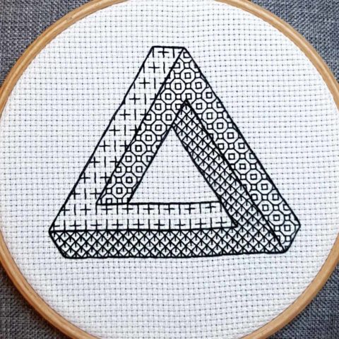 impossible penrose triangle blackwork embroidery on white fabric in a wood hoop