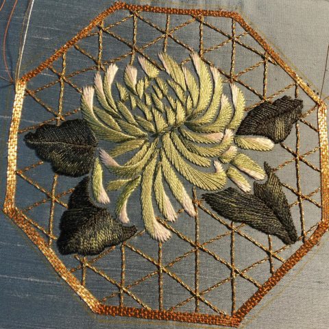A white mum and a lattice of gold thread embroidered on green silk