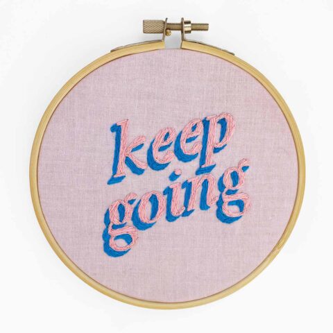 the words "keep going" embroidered in pink and blue on lavender fabric