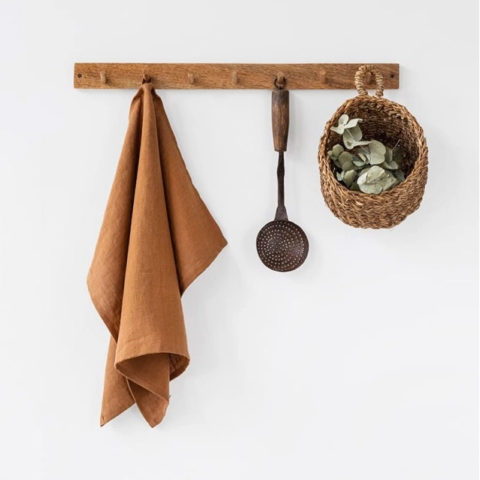 cinnamon colored tea towel hangin on a wooden wall peg