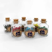Six tiny jars with cork stoppers holding little house glass head pins