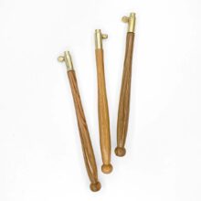 three natural wood tambour handles with brass caps on a white background