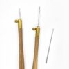 two natural wooden tambour handles showing needles inserted at different lengths next to a loose needle