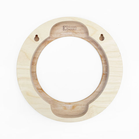 The back of a circular blond wood hoop frame showing the spaces to insert the embroidery hoop and nails for hanging