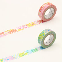 Two rolls of washi tape unwound to show colorful dot patterns in warm and cool tones