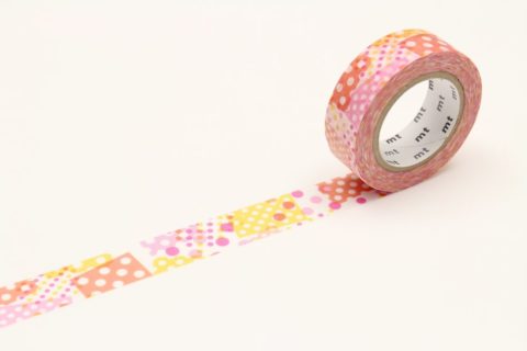 a roll of washi tape unwound to show colorful dot patterns in warm tones
