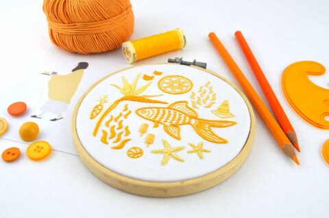 Several folk art objects embroidered in orange in a wooden hoop