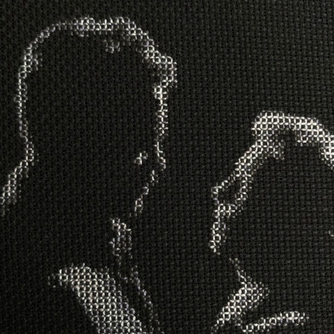 A close up of orson welles and loretta young dimly lit stitched in grayscale on black fabric