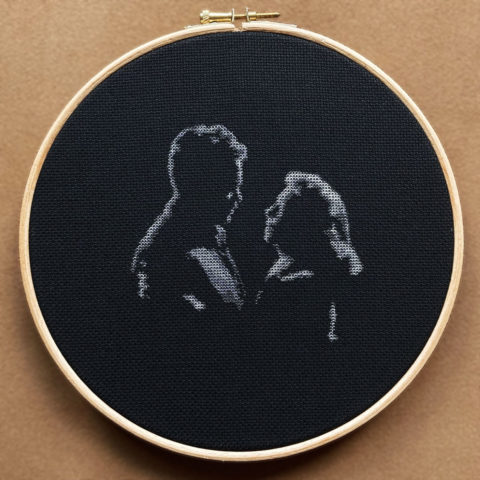 orson welles and loretta young dimly lit stitched in grayscale on black fabric in a wooden embroidery hoop