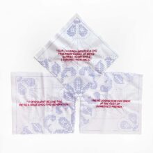 three quotations about gun violence embroidered in red on white and blue squares of fabric