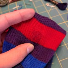 red darning mend in a striped sweater sleeve