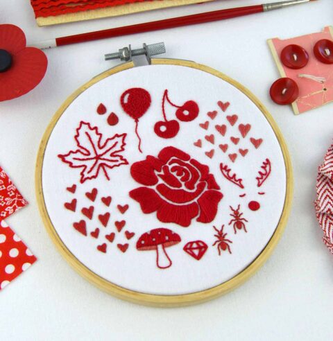 Several folk art objects embroidered in red in a wooden hoop