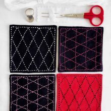 a set of four sashiko stitched coasters in red and navy with supplies laid out above