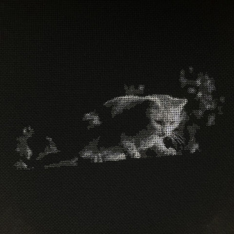 A white cat looking down from a garden fence at night stitched in grayscale on black fabric