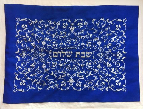 shabbat shalom scrollwork cross stitched in white and silver on a royal blue challah cover