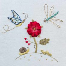 a flower and little garden bugs embroidered on white twill