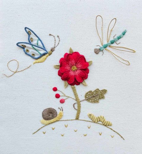 a flower and little garden bugs embroidered on white twill