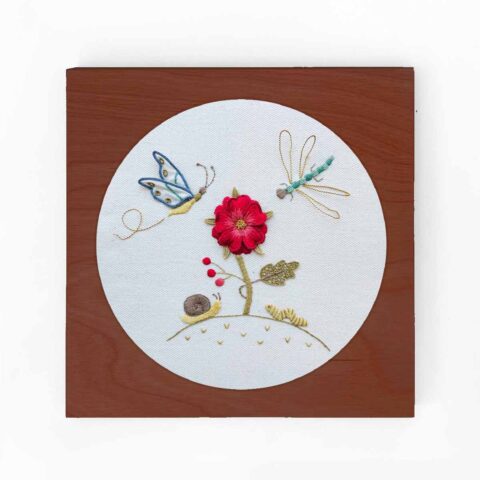 stumpwork flower and insect embroidery inside a square wood hoop frame with caramel stain finish