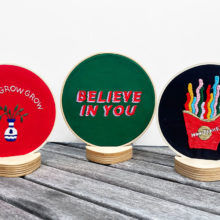 three embroidery hoops propped up for display in small triangular wooden stands