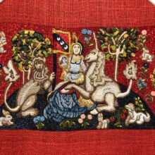 A very detailed embroidery resembling a flemish tapestry showing a lady seated with a lion and a unicorn