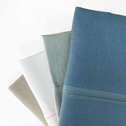 A fan of folded linen fabric in white gray natural blue
